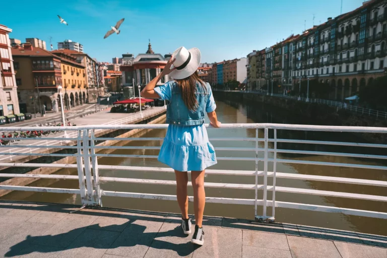 Bagfra ses ung turistkvinde med hvid solhat gå tur i Bilbao by. Sommerferie i Spanien. Foto i høj kvalitet