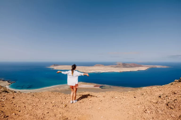 Donna viaggiatrice felice e punto panoramico verso La Graciosa dall'isola di Lanzarote