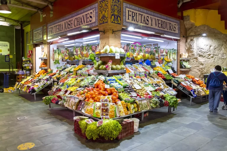 Vendedores y puestos de frutas, verduras, carne y hortalizas en el colorido y vibrante Mercado de Triana o Mercado di Triana, en el histórico barrio de Triana de la ciudad andaluza de Sevilla, España.