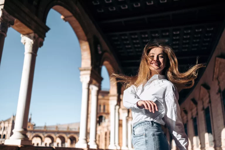 Lachende junge Frau bei der Besichtigung von Sehenswürdigkeiten in Sevilla, Spanien